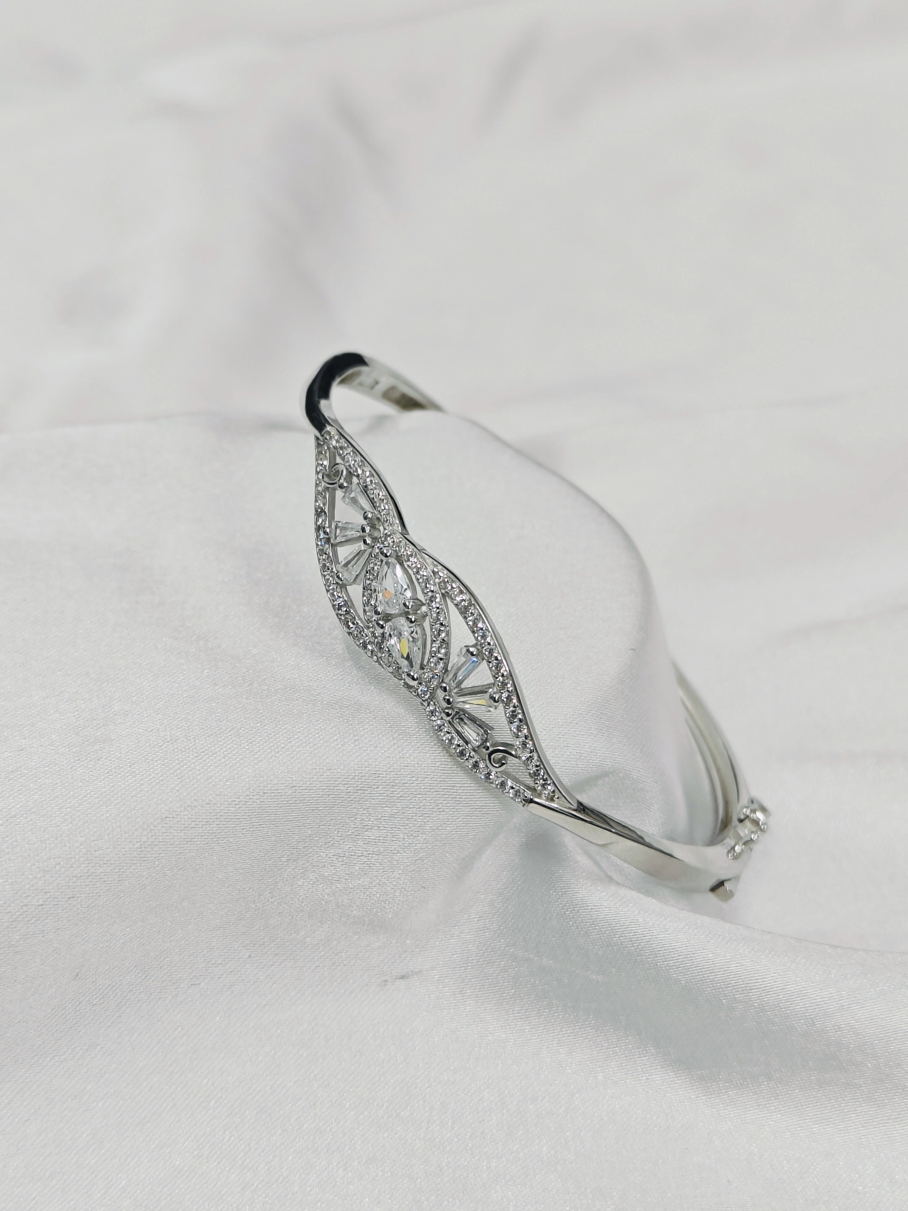 Silver bracelet with intricate design on a white fabric background